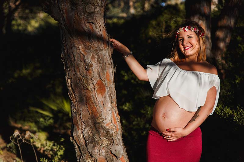 portada sesión de foto de embarazada, madre junto a un árbol enseñando la barriga