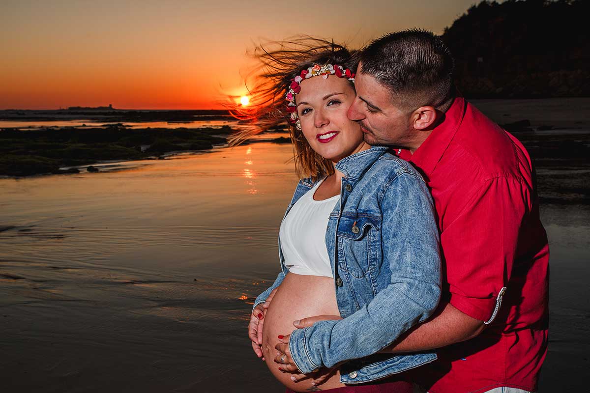 fotos del book de embarazada de Celia en la playa de Cádiz, con su marido abrazándola por detrás con las manos en su barriga.